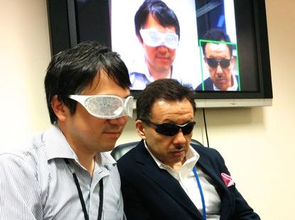 Staffers at the National Institute of Informatics in Tokyo on August 11, 2015, show how a facial recognition system can identify someone wearing sunglasses (right) but not someone wearing the Privacy Visor (left), developed at the institute. 